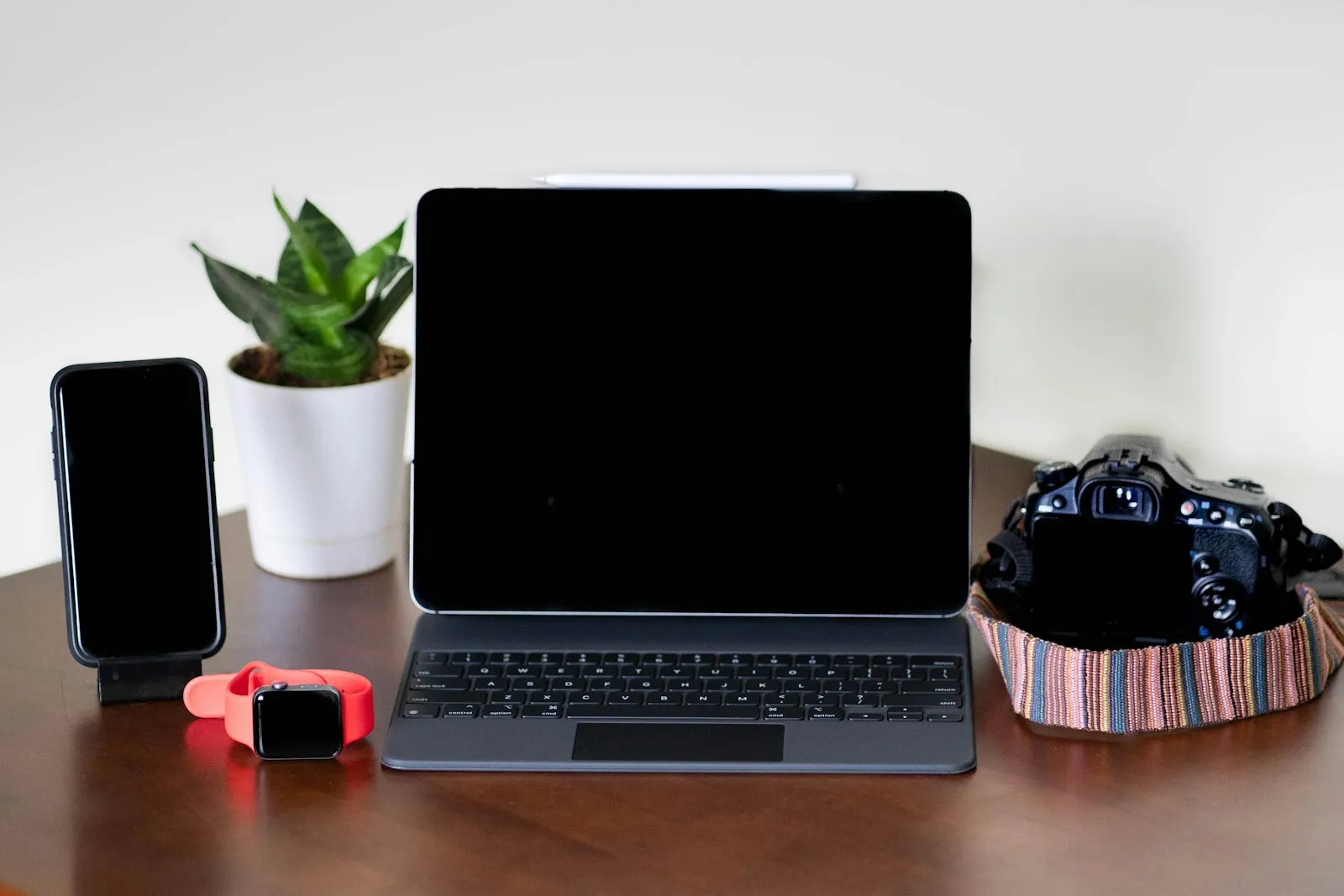 A laptop, phone and plant on a wooden desk