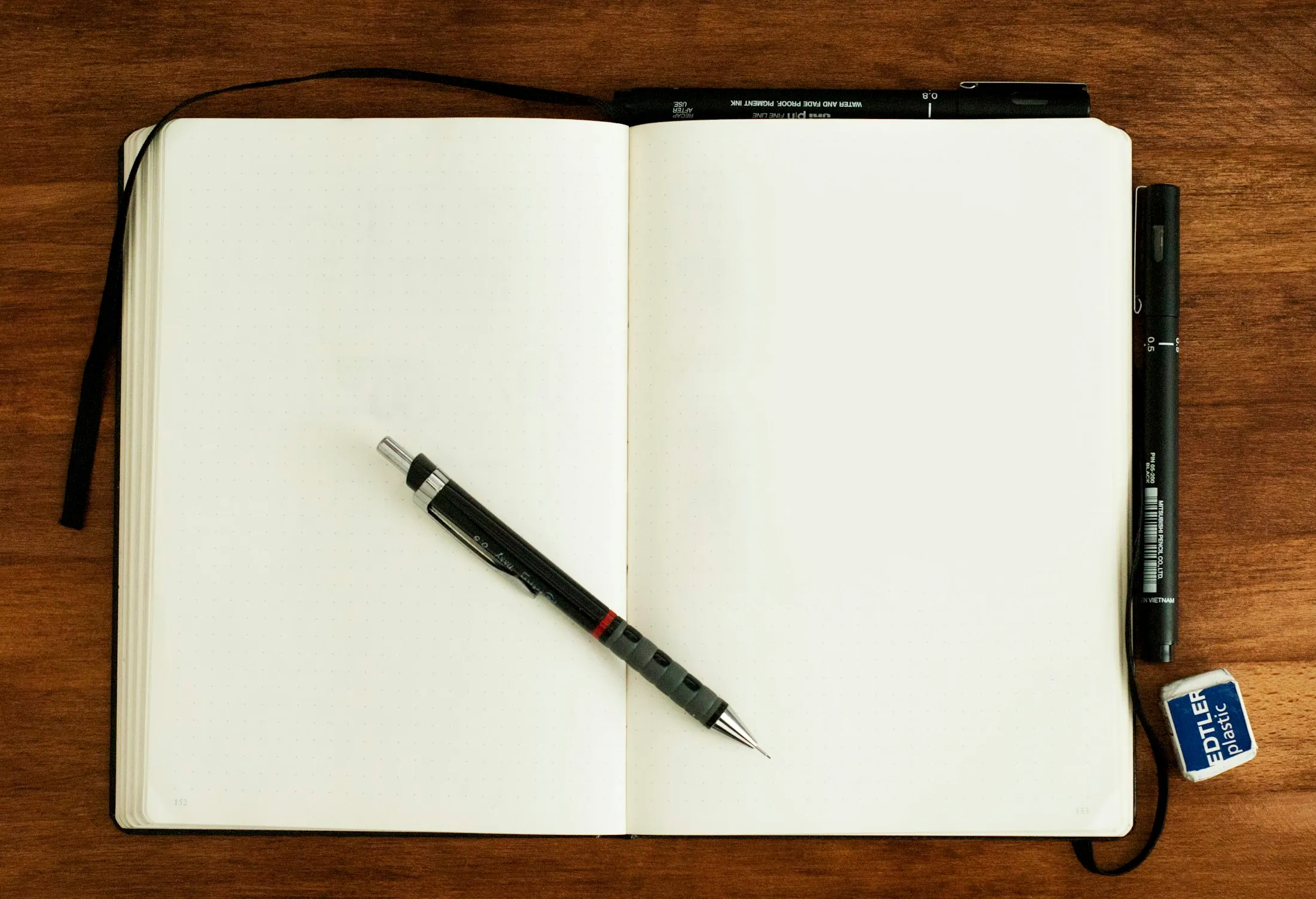 An open notebook and pen on a wooden desk