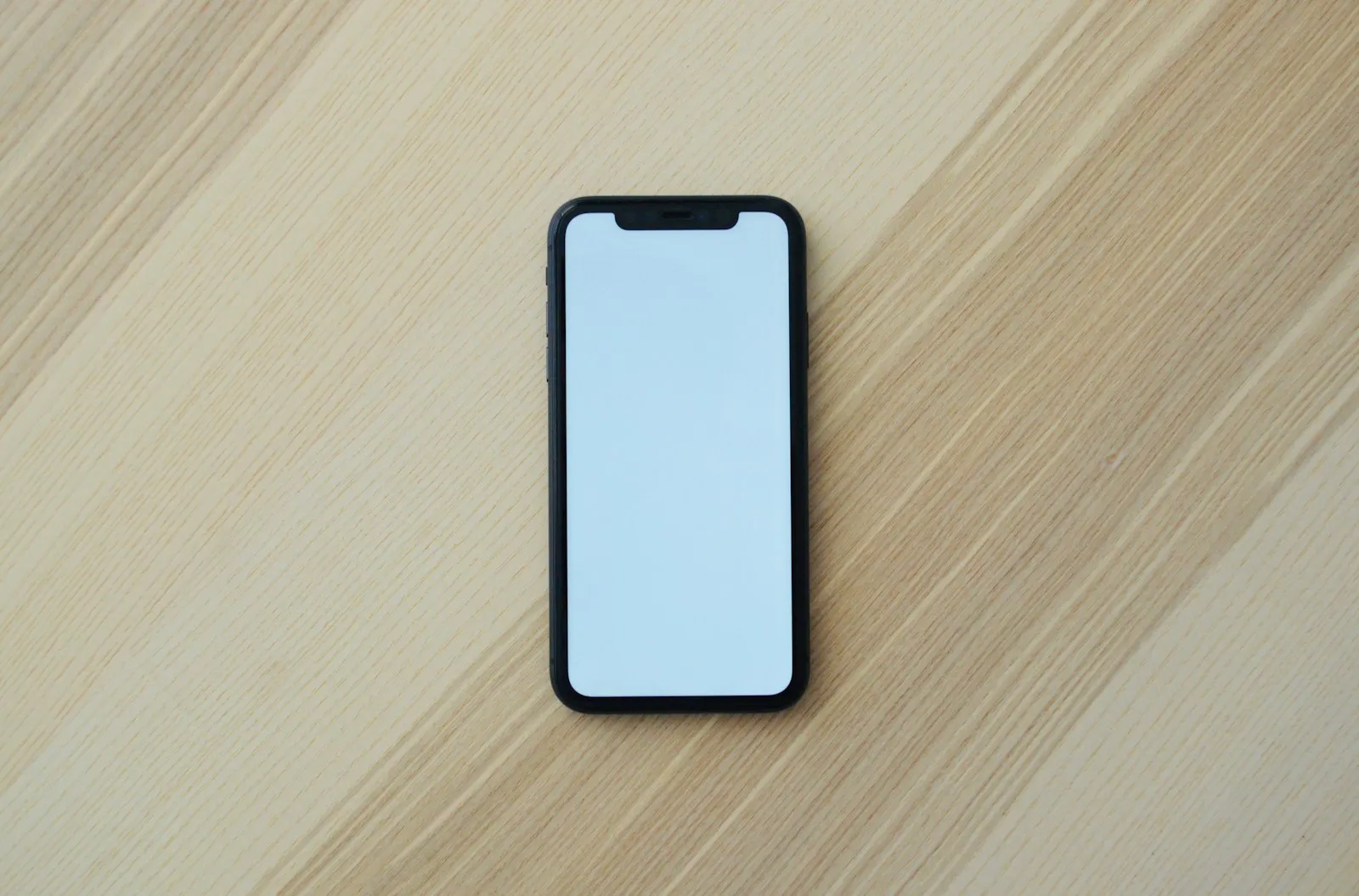 A smartphone lying on a light wooden table
