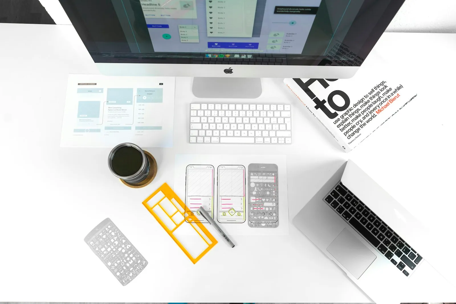 Wireframes, app sketches and a computer on a white desk